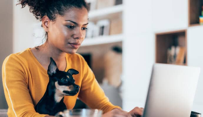 Frau am Laptop mit Hund auf dem Schoß