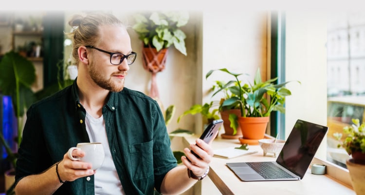 Man mit Tasse und Mobiltelefon.