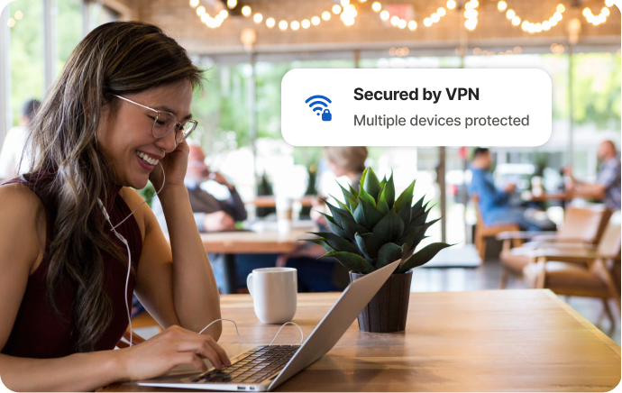 Frau in Café schaut lachend auf Laptop-Bildschirm